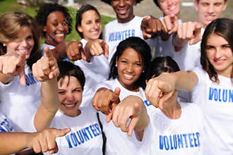 Happy volunteer group pointing towards camera