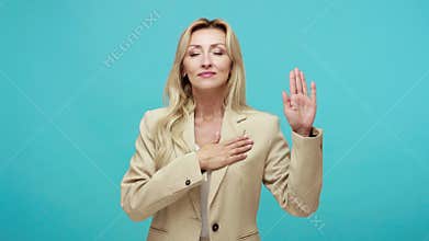 Responsible adult blond woman in business style suit holding hand on chest swearing and promising proud to be part of her country