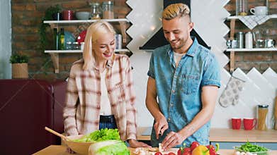 Smiling young couple cooking together vegetarian meal in the kitchen at home