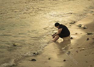 Old albanian woman alone on the beach in sunset.
