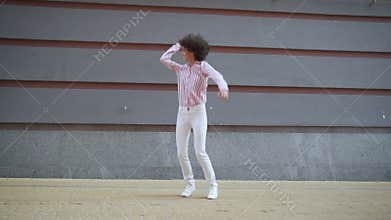 Happy funky young woman dancing jumping on urban wall background, slow motion.