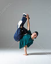 Cool b-boy dancing on one hand in studio isolated on gray background. Breakdance poster