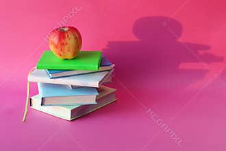 Back to school, apple on a stack of books, bright background with space for an inscription, the concept of learning