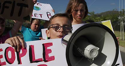 Group of kids with climate change signs and megaphone in a protest