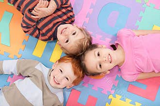 Children lying on backs on fun kids alphabet mat