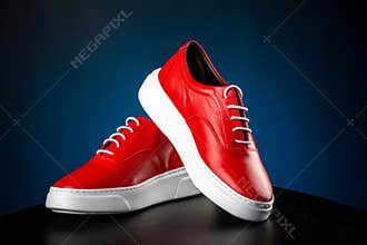 Mens red leather shoes with white soles on blue background