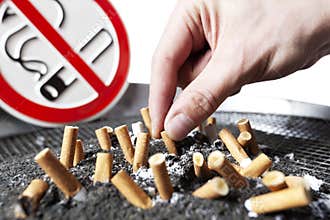 Cigarette stubs in ash and no smoking sign.
