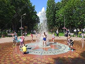 Children have a fun with city fountains during summer heat
