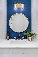 A white and blue half bathroom with gold accents.