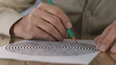 Senior man taking maze test, therapy people with dementia, diagnostics, close-up