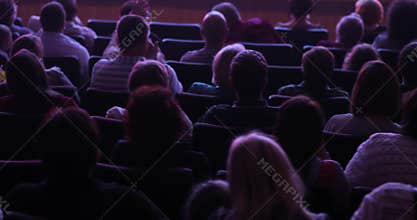 Viewers watching staging on theatre scene sitting in audience hall, back view.