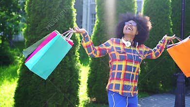 Cheerful african american woman with an afro hairstyle with packages after shopping slow mo