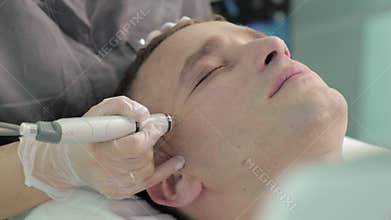 Relaxing dark-haired man during the hydrofacial vacuum care procedure slow motion