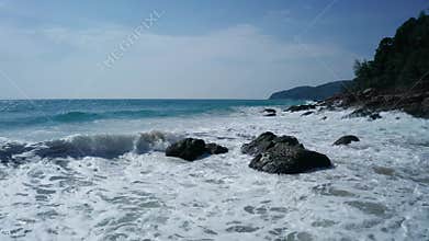Aerial low view of ocean`s beautiful waves and rocky coast with greenery
