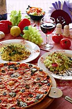 Italian food setting with pizza, pasta and wine