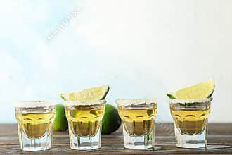 Tequila shots with salt and lime slices on wood table