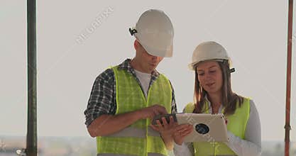 Engineers designers stand on the roof of the building under construction and discuss the plan and the progress of