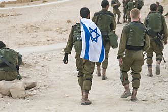 Back shot of several soldiers of israel army walking with israel national flag. Military man bearing israel flag on his shoulder