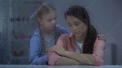 Little girl supporting depressed mother after divorce, break up, rainy weather