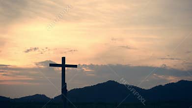 Conceptual wood cross or religion symbol shape over a sunset sky
