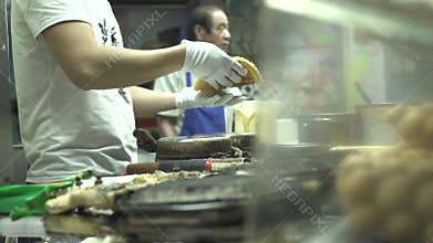 Hong Kong city, China - June, 2019: cook baking waffles in street food cafe. Traditional street fast food in asian city