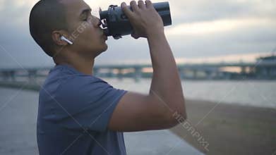 African american athlete drinking water during running workout.