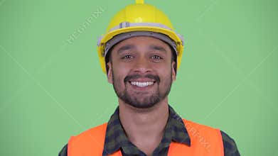 Face of happy young bearded Persian man construction worker smiling