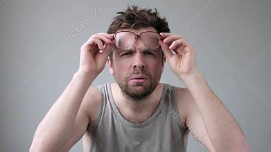 Young man looking through huge glasses in shock with surprise expression.