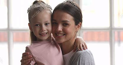 Loving mum embracing cute small kid daughter wearing crown