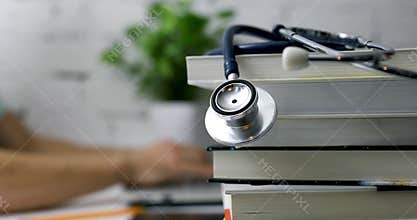 Stack of books with stethoscope and medical student