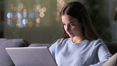 Serious girl browsing laptop in the night