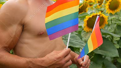 Handsome male athlete torso man with beautiful muscles holds a rainbow Gay pride LGBT flag in his hands symbol of