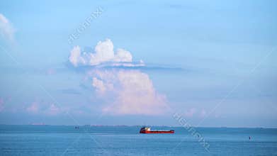Breathtaking seascpe with a sailing red barge on blue cloudy sky on the background, water transport concept. Shot. Cargo