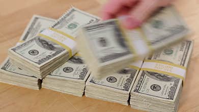 Man Lays Down Stacks of One Hundred Dollar Bills Into A Pyramid On Table