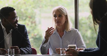 Middle aged female company boss speak during corporate group meeting