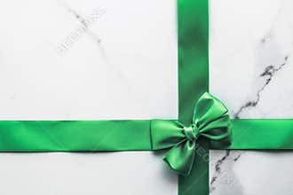 Green silk ribbon and bow on marble background, St Patricks day present or Christmas glamour gift decor for luxury digital brand,