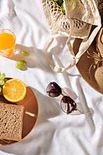 Picnic background with bag, bread and straw hat, glasses, orange juice, phone on white background