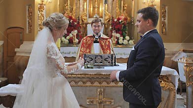 Lida, Belarus - August 4, 2019: The groom puts a ring on his bride. The wedding ceremony in the Catholic Church.