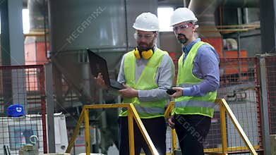 Professional factory workers at factory facility. People work at a brick plant, using laptop.
