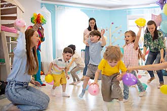 Happy children and their parents entertain and have fun with color balloon on birthday party