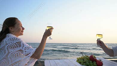 Attractive couple by the sea with wine and fruit enjoying each other`s company