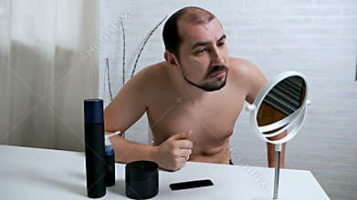 Handsome, young, man. Takes care of his face. Close-up of a young man sitting in front of a mirror clutching a pimple on