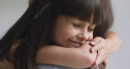 Happy cute adopted kid girl hugging foster care parent mother