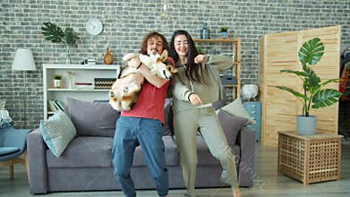Happy couple dancing at home holding welsh corgi pembroke dog having fun together