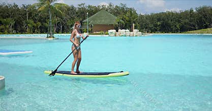 Woman floating on paddle board in large swimming pool