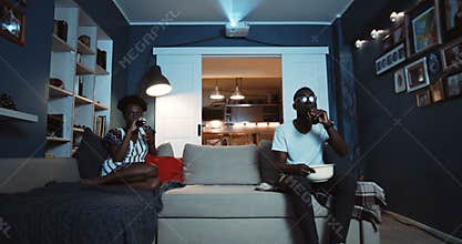 Young casual black couple sit separately on couch watching movies not talking after fighting and quarreling slow motion.