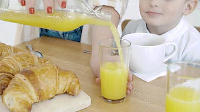 Close-up of female hands pouring orange juice into a glass. Breakfast.