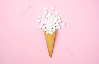 Waffle cone with white mini marshmallows on a pink background