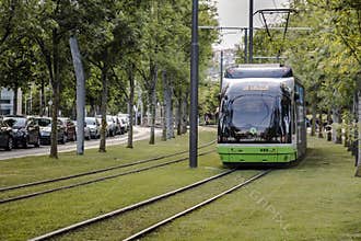 The tram runs through the city center on tracks surrounded by grass.