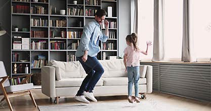 Active cheerful dad dancing having fun with kid at home
